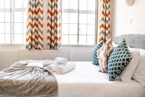 ein weißes Bett mit Handtüchern und Kissen darauf in der Unterkunft Urban Escape - Stylish 3Bedroom in Watford Center in Watford