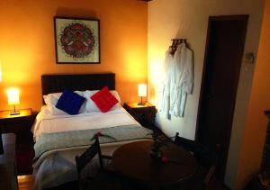 Un dormitorio con una cama con almohadas de colores y una mesa. en Pousada Bocaina, en São Pedro da Serra