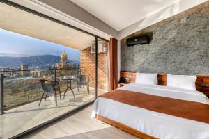 a bedroom with a bed and a balcony with a view at Ivy Hotel in Tbilisi City