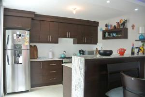 a kitchen with wooden cabinets and a stainless steel refrigerator at Tu confort en Los Andes in Baños