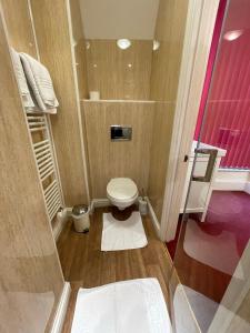 a small bathroom with a toilet and pink walls at Môr Wyn Guest House in Barmouth