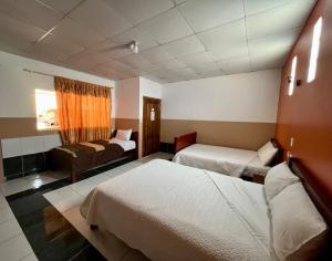 a hotel room with two beds and a couch at Hostal Alpachaca - New Quito Airport in Tababela