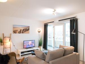 a living room with a couch and a tv at Helena at Sea Apartments in Scheveningen +7 photos