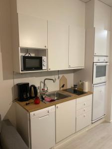a kitchen with white cabinets and a sink and a microwave at Ihana huoneisto juna aseman vieressä. in Vantaa