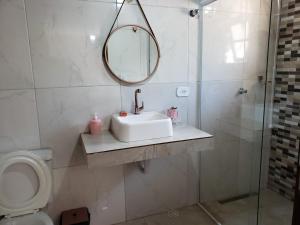 La salle de bains est pourvue d'un lavabo, d'un miroir et de toilettes. dans l'établissement Suite Campos do Jordão, à Campos do Jordão