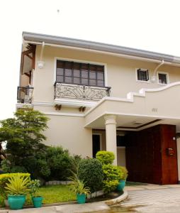 a white house with a balcony and plants at Eagle Ridge Family Vacation House in General Trias