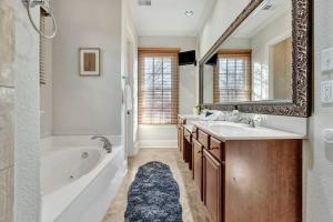 ein Badezimmer mit einer Badewanne, einem Waschbecken und einem Spiegel in der Unterkunft Luxury home with outdoor patio and game room in Memphis