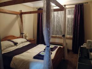 sypialnia z łóżkiem z baldachimem i oknem w obiekcie Littleholme w mieście Potter Heigham