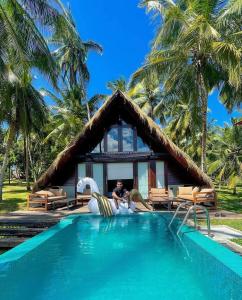 un uomo seduto di fronte a un resort con piscina di Coconut Escapes a Kurunegala