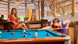 a woman playing pool with a cue in a pool table at Cariblue Beach and Jungle Resort in Puerto Viejo