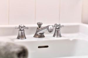 a bathroom sink with two faucets on it at Maison Garnier Hôtel de Charme Biarritz in Biarritz