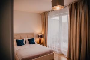 een slaapkamer met een bed met blauwe kussens en een raam bij JBHotels Apartament Premium Plus in Szczecin