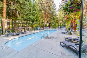 a large swimming pool with chairs and trees at Alpenglow Lodge by Elevate Vacations in Whistler