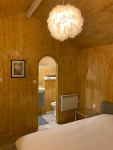 a bedroom with wooden walls and a chandelier at chalet paradisiaque en bord de Marne Proche de Disneyland in Isles-lès-Villenoy