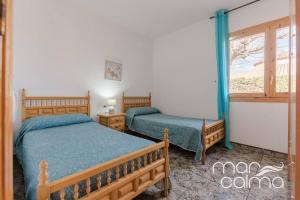a bedroom with two beds and a window at Villa La Roca by MarCalma in Les tres Cales +13 photos