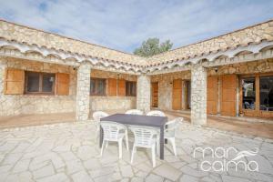 a patio with a table and chairs in front of a building at Villa La Roca by MarCalma in Les tres Cales
