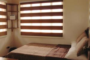 a bedroom with a bed and a window with blinds at Eagle Ridge Family Vacation House in General Trias