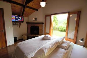 a bedroom with a large bed and a fireplace at Pousada Aguia da Montanha in Monte Verde