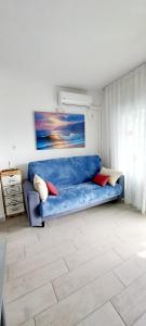AptoVistas al mar-Font de Mar en Cap de Salou في سالو: أريكة زرقاء في غرفة المعيشة مع لوحة