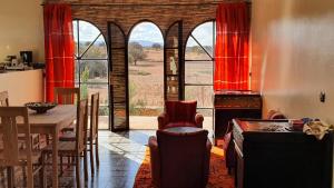 uma cozinha e sala de jantar com cortinas vermelhas e uma mesa em Belle villa Baldi à la campagne d'Essaouira em Essaouira
