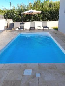 ein blauer Pool mit Stühlen und einem Sonnenschirm in der Unterkunft Villa avec piscine chauffée entre terre et mer in Folelli