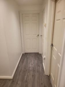 an empty hallway with a white door and wooden floors at Vetrelax Basildon Crosse Apartment in Basildon