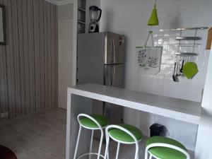 una cocina con encimera con taburetes verdes en Al Campinas X Av.Paulista, en São Paulo