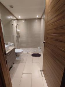 a bathroom with a shower and a toilet and a door at LUXURY 3 bedroom apartment with pool, Nouaceur, Morocco in Derroua