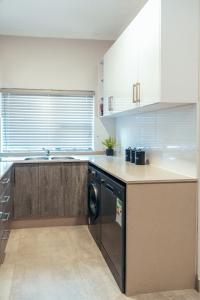 a kitchen with a sink and a dishwasher in it at Sarona City Apartment A306 in Gaborone +20 photos