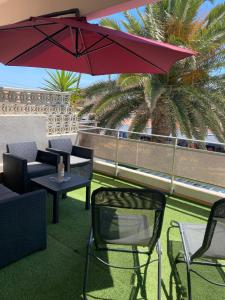 un patio con tavolo, sedie e ombrellone di La palmera a Frontignan