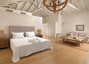 a white bedroom with a large bed and a couch at Camvillia Resort Messinia in Vounaria