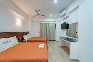 Cette chambre comprend 2 lits et une télévision à écran plat. dans l'établissement Mi Querida Maribel Hotel, à Santa Cruz Huatulco