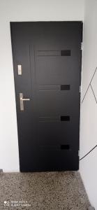 a black door in a room with a wall at Apartament Szóstka nad Sołą in Czaniec