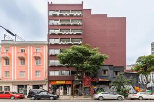 a tall red building with cars parked in front of it at Tabas - Edifício União Continental in Sao Paulo