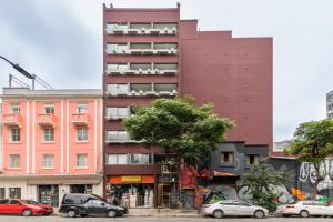 un edificio rojo alto con coches estacionados frente a él en Tabas - Edifício União Continental, en São Paulo