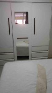 a bedroom with white cabinets and a bed with a mirror at Seu lar em Bonito-PE in Bonito