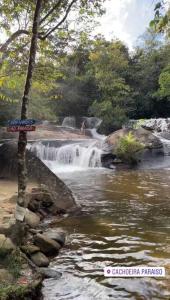a waterfall with a sign in front of a river at Seu lar em Bonito-PE in Bonito