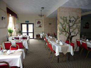 a dining room with white tables and red chairs at Woodlands Hotel in Birmingham
