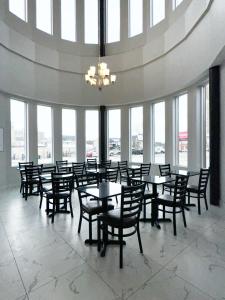 a dining room with tables and chairs and windows at Premier Inn & Suites - Downtown Hamilton in Hamilton