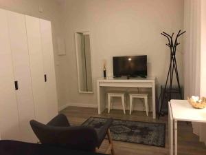 Charming Studio Apartment in Campolide - 2F في لشبونة: غرفة معيشة مع تلفزيون وطاولة مع كرسي