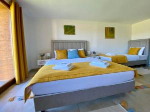 a bedroom with two beds with yellow and blue pillows at Tenger-szem Panzió és Lovasudvar in Zánka +83 photos