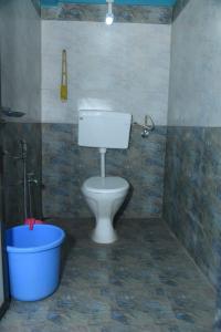 a bathroom with a toilet and a blue bucket at NISARG HOME STAY near Bus Stand Malvan in Malvan