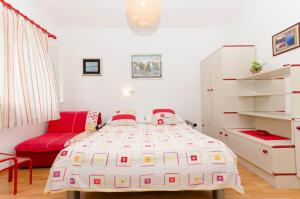 a bedroom with a bed and a red couch at Apartments Simon in Bol