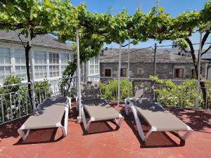 two swinging chairs under a tree on a patio at Pension-Albergue Don Alvaro in Sarria