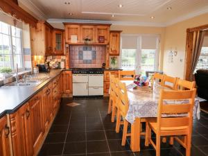 uma cozinha com armários de madeira e uma mesa com cadeiras em Willow Tree Farm House em Newry