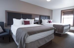 a hotel room with two beds and a chair at Hotel Arvon in Great Falls