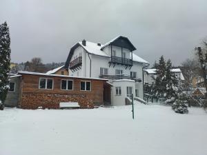 une grande maison avec de la neige au sol dans l'établissement Milusia Muszyna, à Muszyna