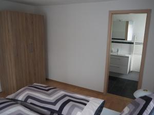 1 dormitorio con espejo, 1 cama y lavamanos en Ferienwohnung am Bach, en Amtzell