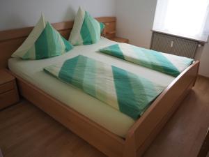 Una cama con almohadas verdes y blancas. en Ferienwohnung Schlossblick, en Amtzell