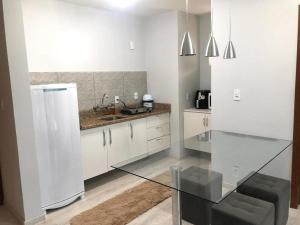 Il comprend une cuisine équipée d'une table en verre et d'un réfrigérateur. dans l'établissement Saint Sebastian Flat 213 - Com Hidro! até 4 pessoas, Duplex, no centro, à Jaraguá do Sul